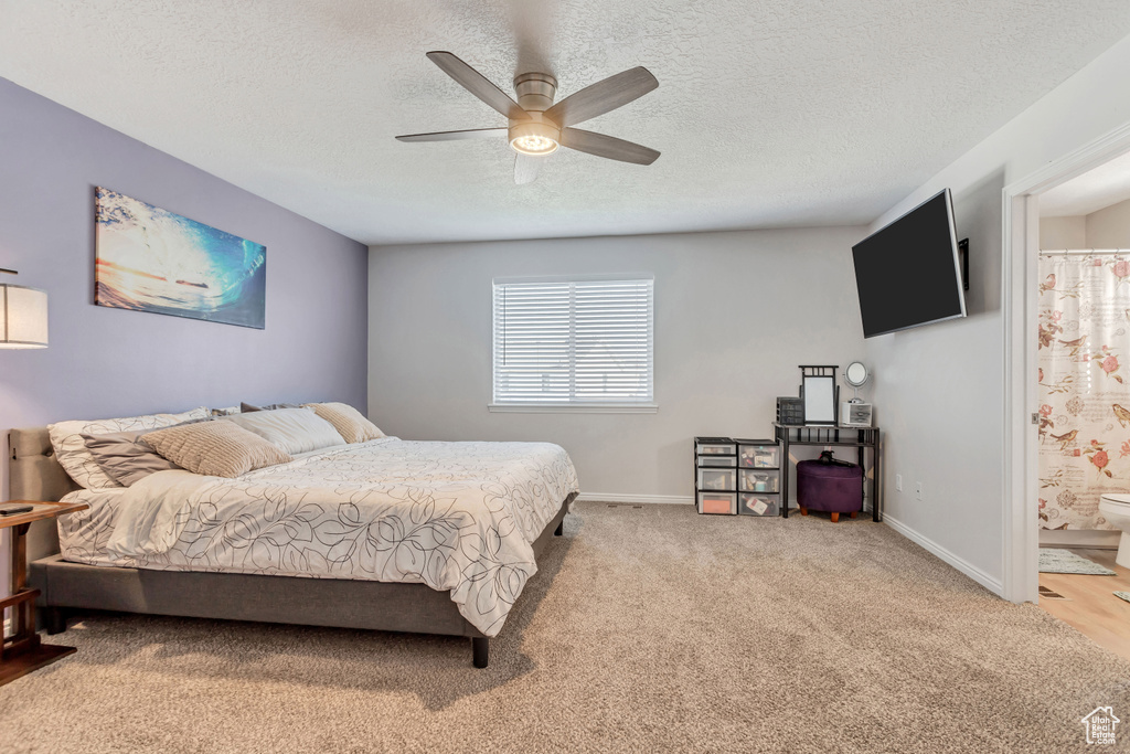 Carpeted bedroom featuring ensuite bath, ceiling fan, and a textured ceiling