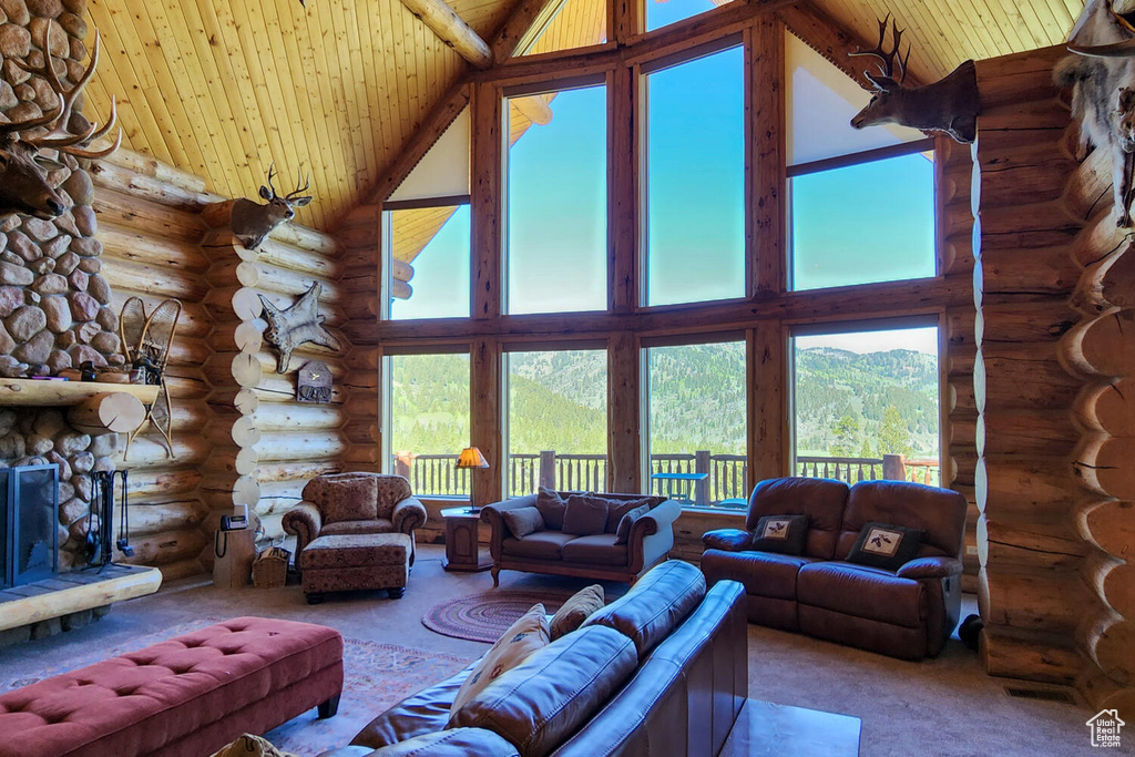 Living room featuring wood ceiling, high vaulted ceiling, log walls, and a stone fireplace