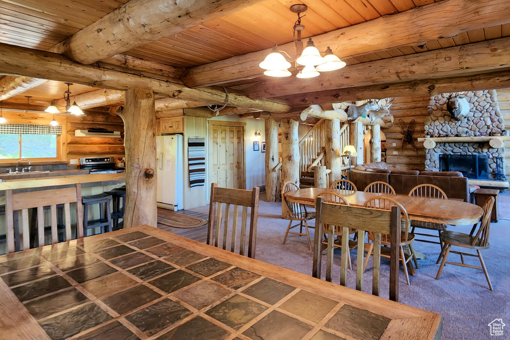 Dining area featuring wooden ceiling, beamed ceiling, a stone fireplace, and rustic walls