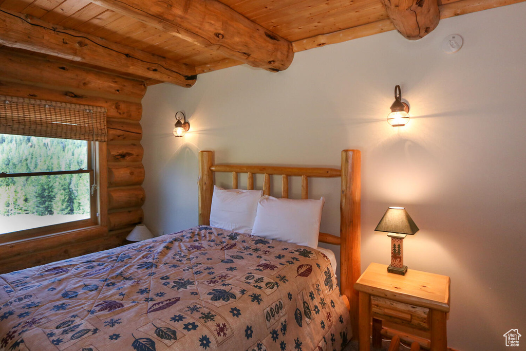 Bedroom with beamed ceiling, wooden ceiling, and rustic walls