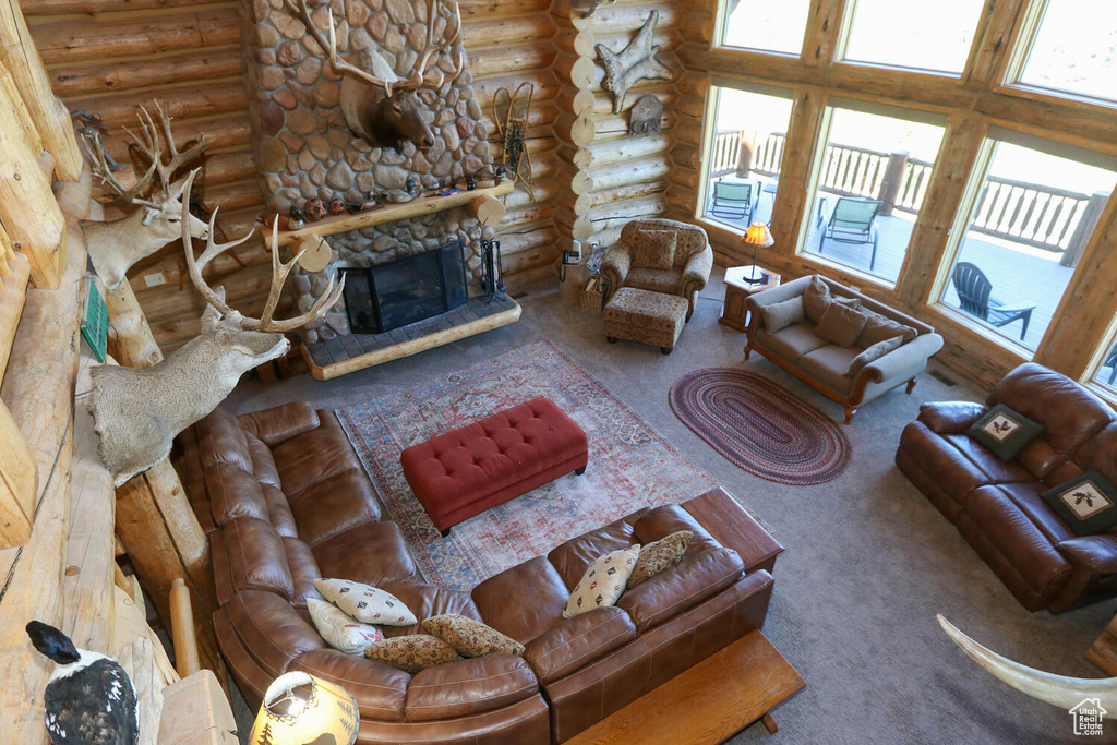 Living room with a fireplace, carpet floors, log walls, and a high ceiling
