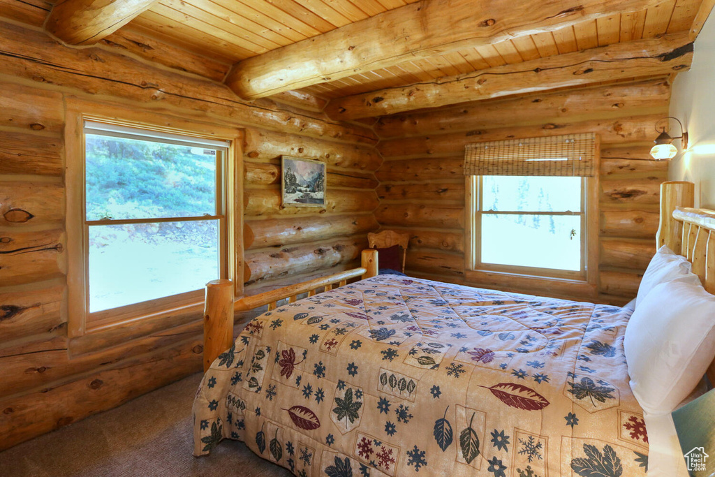 Bedroom with rustic walls, beam ceiling, wooden ceiling, and multiple windows
