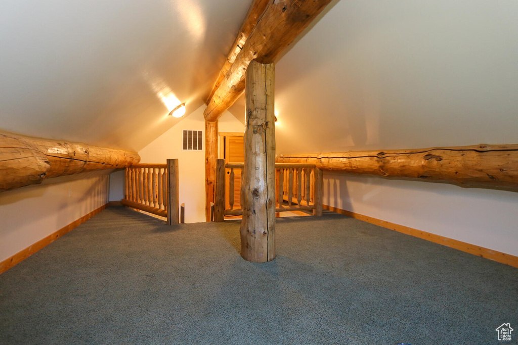 Additional living space featuring lofted ceiling with beams and dark carpet