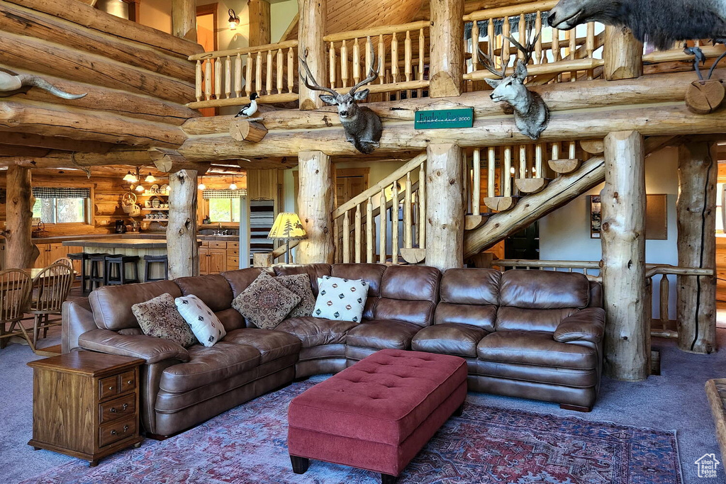 Living room featuring carpet flooring, a towering ceiling, and rustic walls