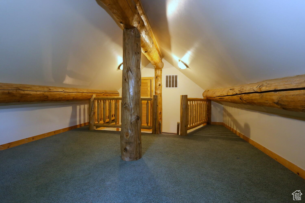 Additional living space with lofted ceiling and dark colored carpet