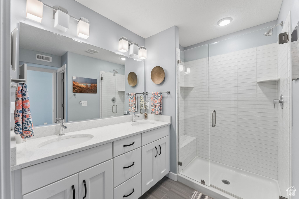 Bathroom with double sink, a shower with shower door, oversized vanity, and tile flooring