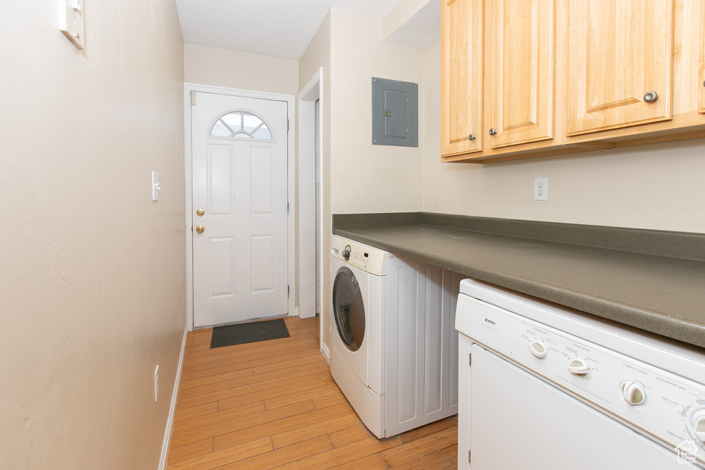 Washroom featuring light hardwood / wood-style flooring, cabinets, and washer and clothes dryer