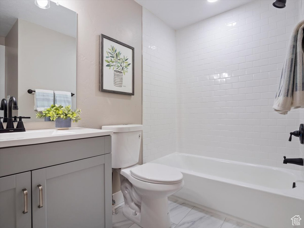 Full bathroom with tile flooring, vanity, tiled shower / bath combo, and toilet