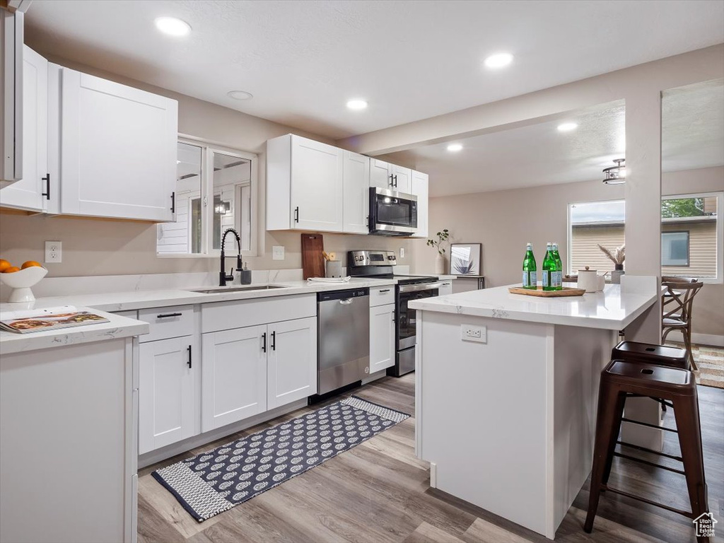 Kitchen featuring white cabinets, sink, a kitchen breakfast bar, and stainless steel appliances