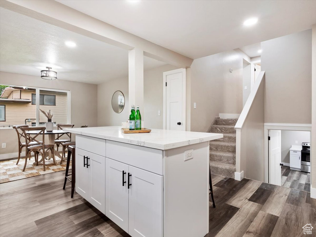 Kitchen with a center island, white cabinetry, a breakfast bar area, and dark wood-type flooring