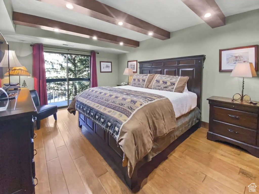 Bedroom with beamed ceiling, hardwood / wood-style flooring, and access to exterior
