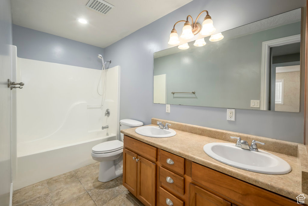 Full bathroom with shower / tub combination, tile flooring, toilet, and double sink vanity