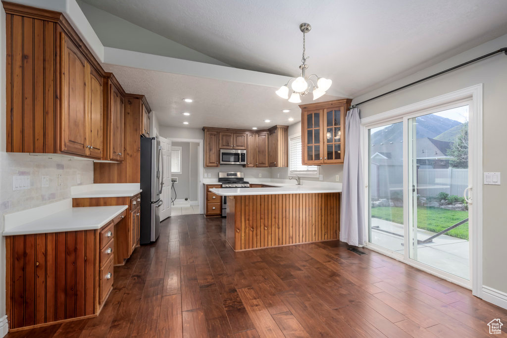Kitchen with appliances with stainless steel finishes, kitchen peninsula, dark hardwood / wood-style floors, and plenty of natural light