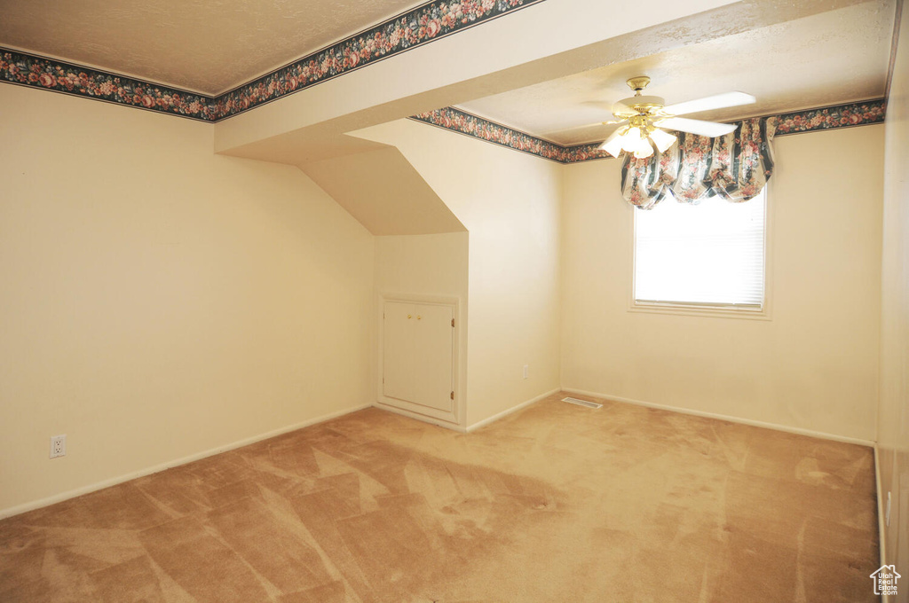Additional living space featuring a textured ceiling, ceiling fan, and light carpet