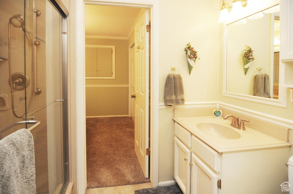 Bathroom featuring walk in shower, crown molding, and large vanity