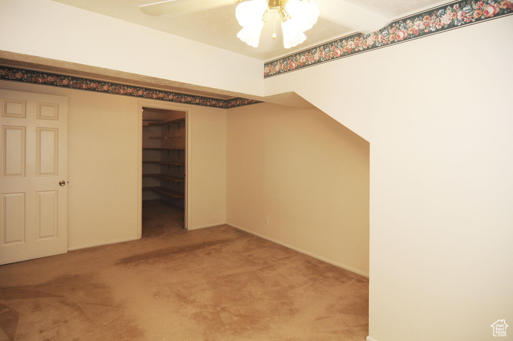 Unfurnished bedroom featuring a closet, a spacious closet, carpet floors, and ceiling fan