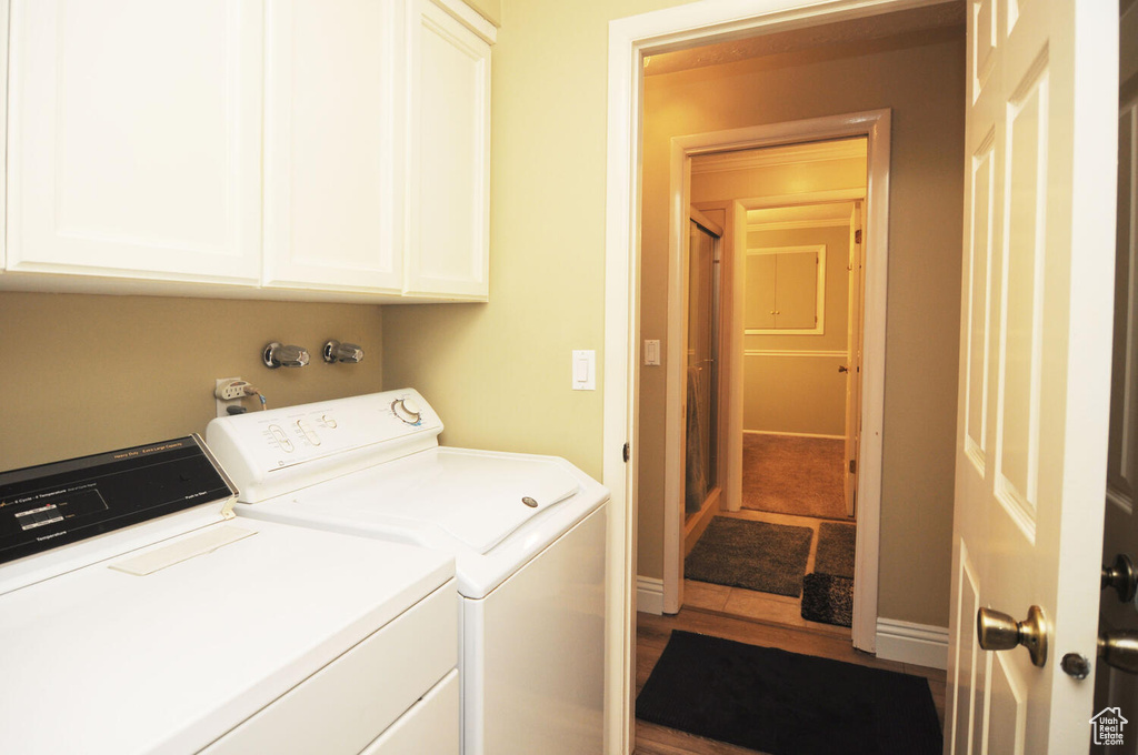Laundry room with cabinets, tile floors, and washing machine and clothes dryer