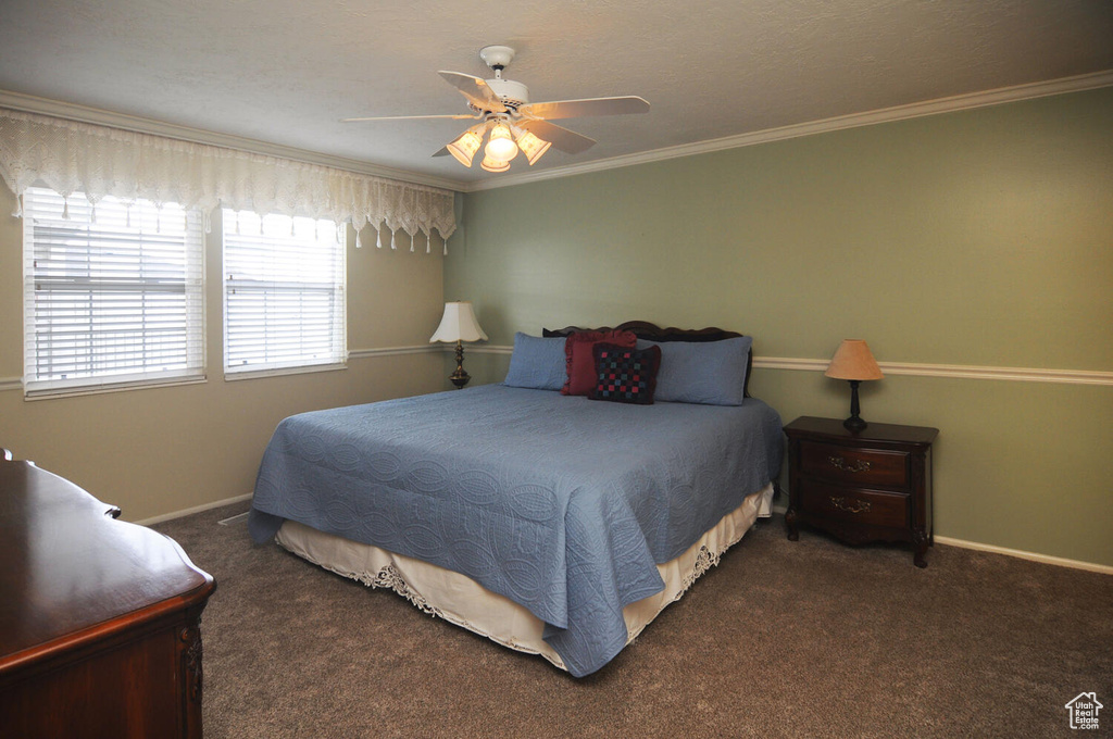 Bedroom with dark colored carpet, ceiling fan, and ornamental molding