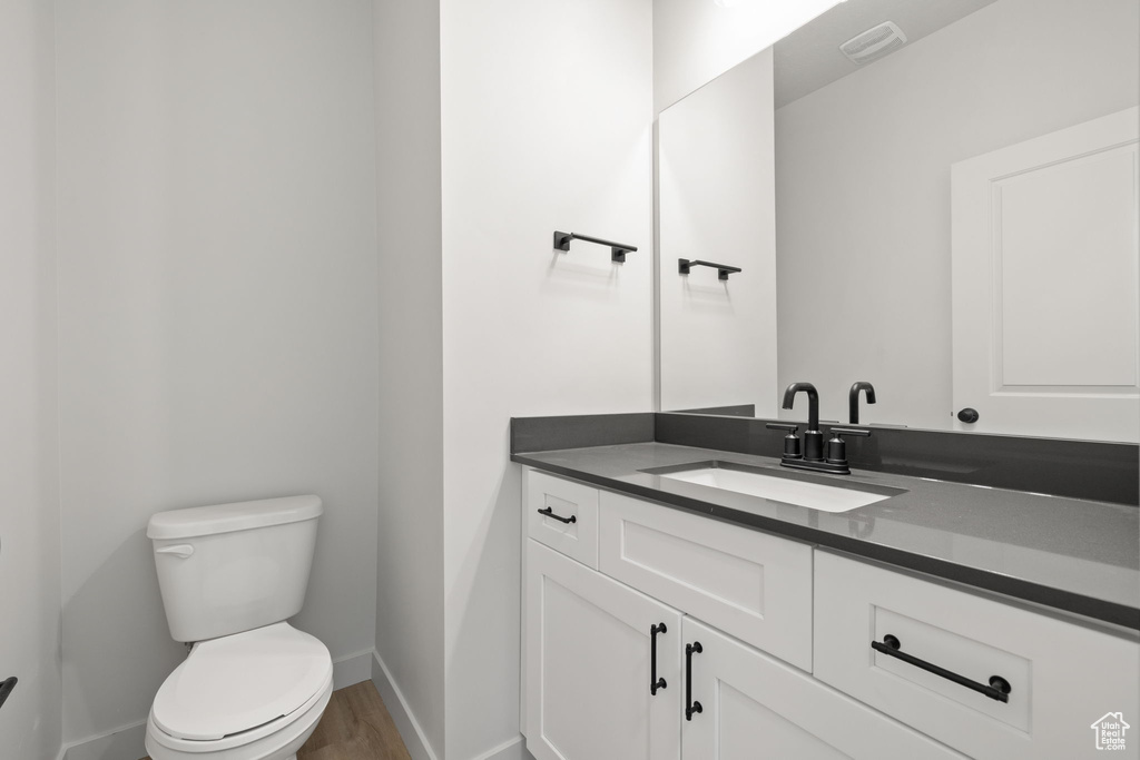 Bathroom with hardwood / wood-style floors, vanity, and toilet