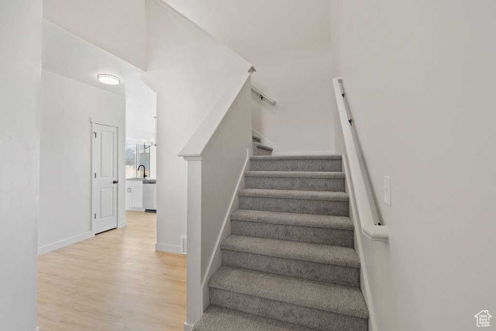 Staircase with a high ceiling, hardwood / wood-style floors, and sink