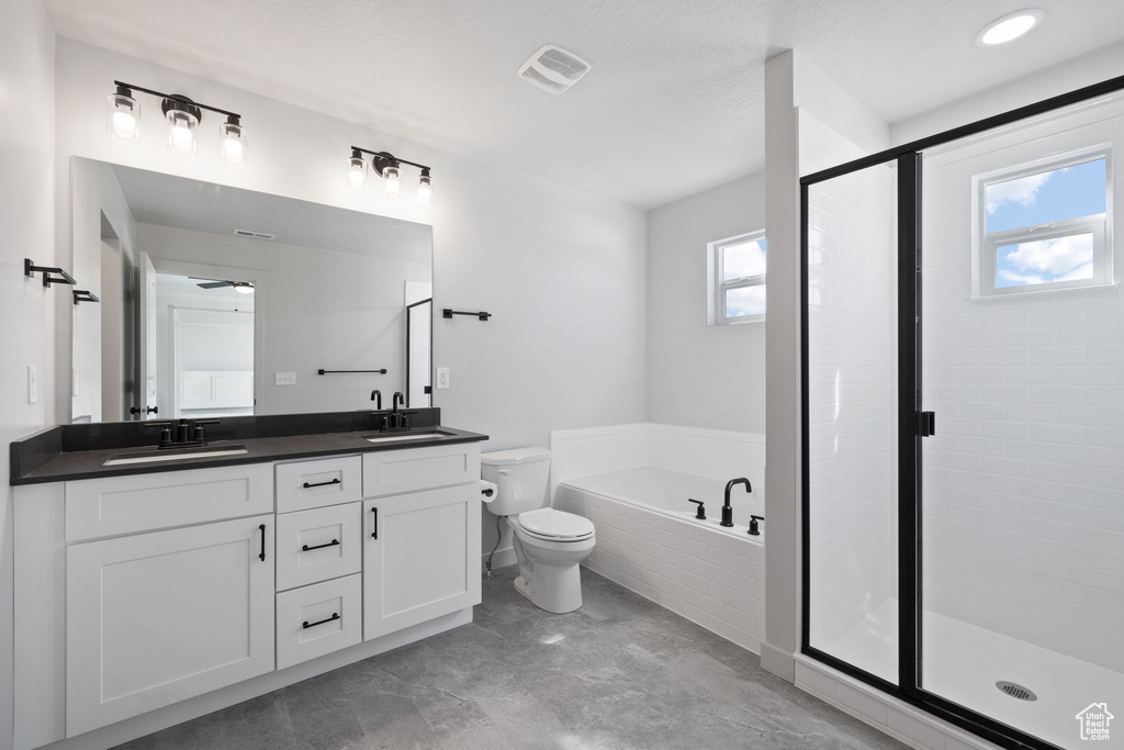 Full bathroom featuring vanity, separate shower and tub, toilet, and a wealth of natural light