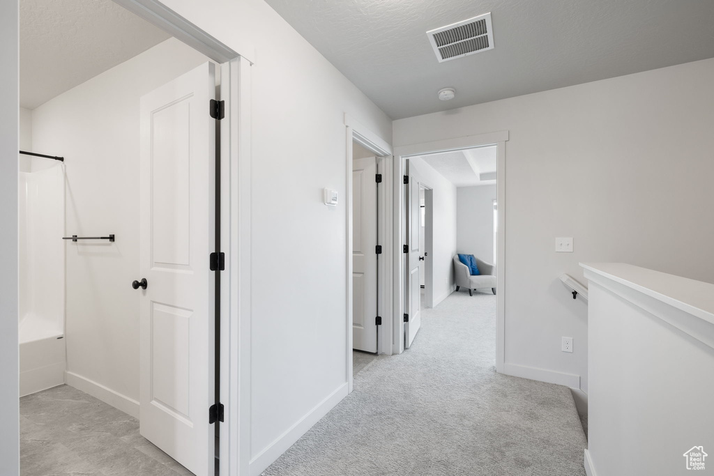 Hallway featuring light carpet