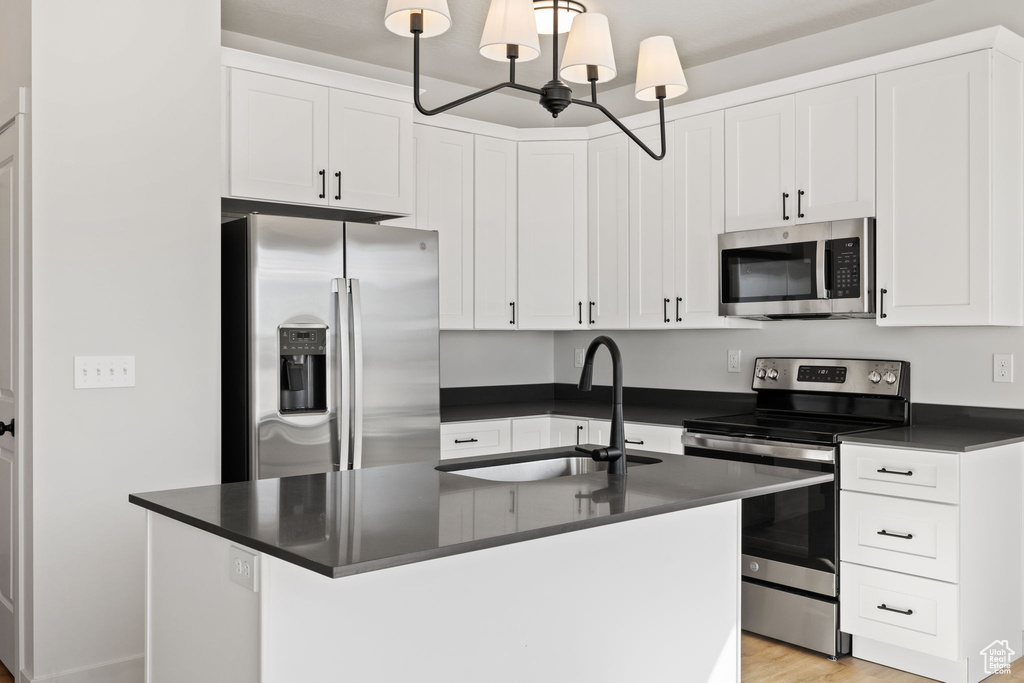 Kitchen featuring decorative light fixtures, a kitchen island with sink, stainless steel appliances, and sink