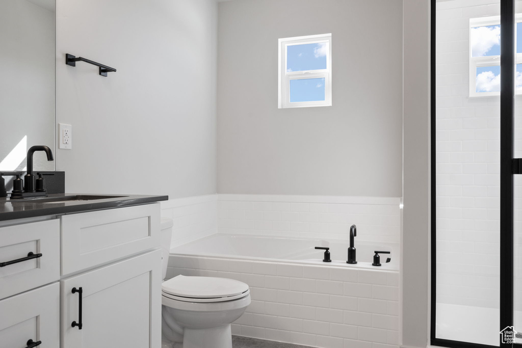 Bathroom featuring vanity, toilet, and a relaxing tiled tub