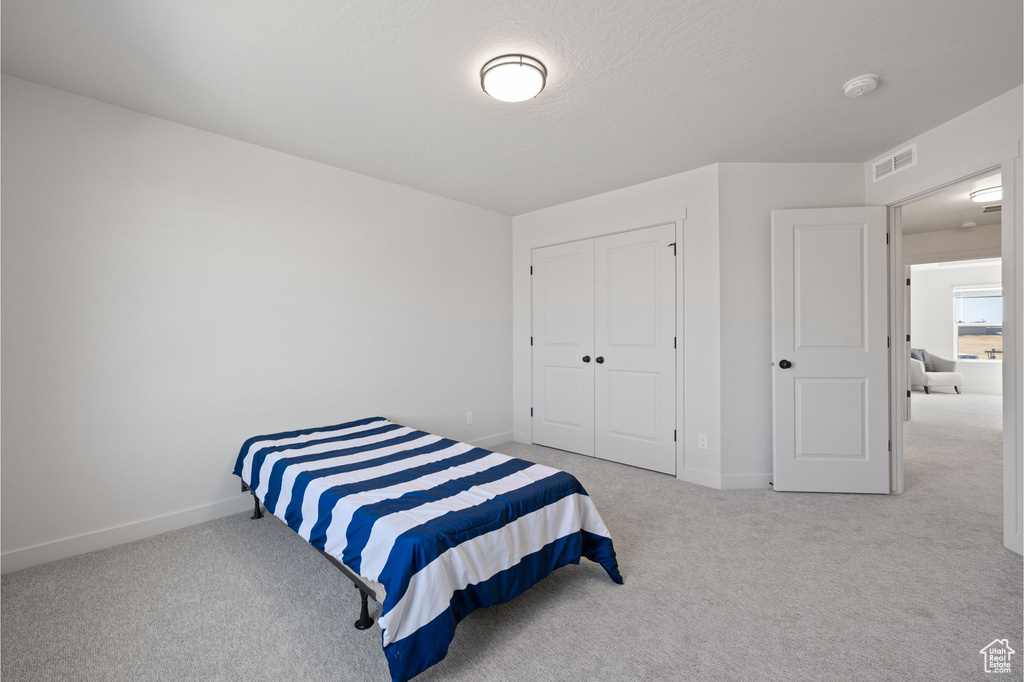 Carpeted bedroom with a textured ceiling and a closet