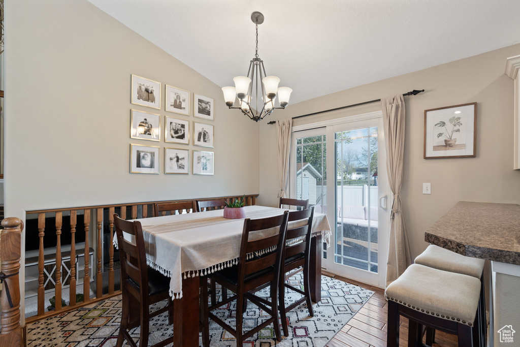 Dining space with a notable chandelier, hardwood / wood-style floors, and vaulted ceiling
