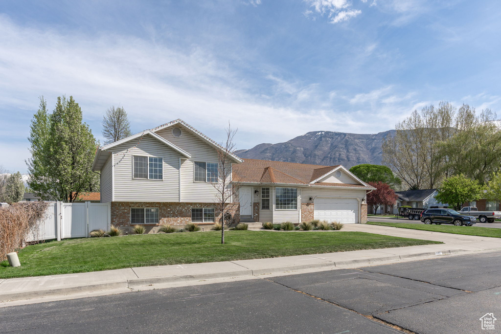 Tri-level home with a garage, a mountain view, and a front lawn