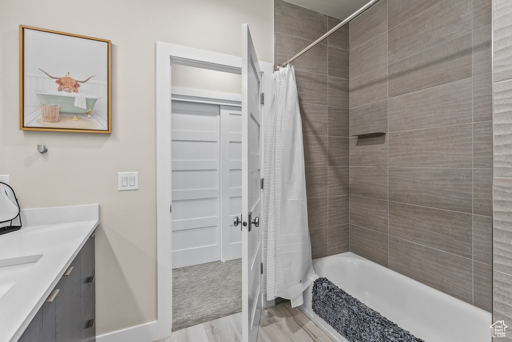 Bathroom featuring shower / bath combo with shower curtain, vanity, and hardwood / wood-style floors