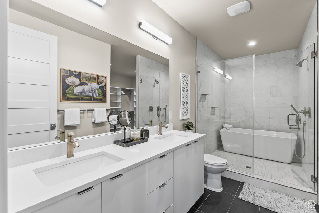 Bathroom with walk in shower, double vanity, tile flooring, and toilet