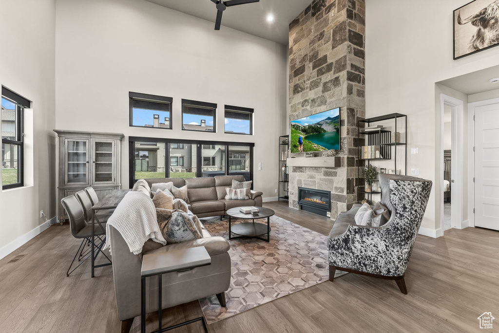 Living room with hardwood / wood-style flooring, a fireplace, and a towering ceiling