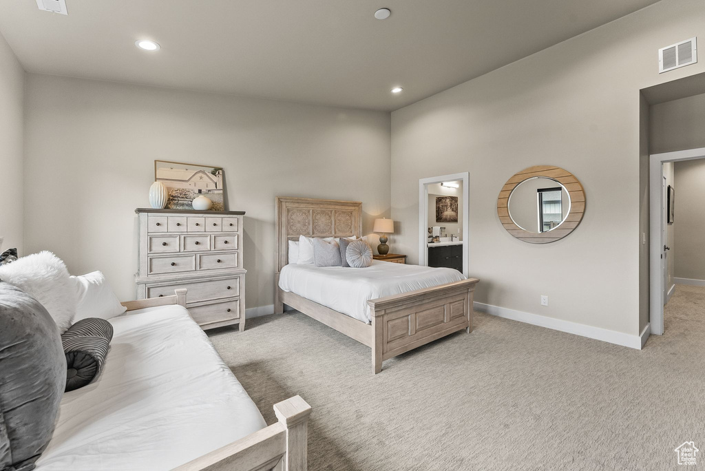 Bedroom featuring light colored carpet and connected bathroom