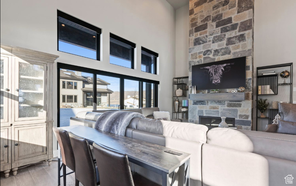 Living room featuring light hardwood / wood-style floors, a towering ceiling, and a fireplace