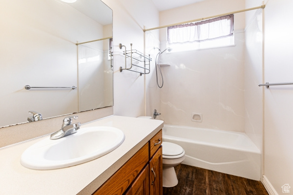 Full bathroom featuring washtub / shower combination, hardwood / wood-style floors, vanity, and toilet