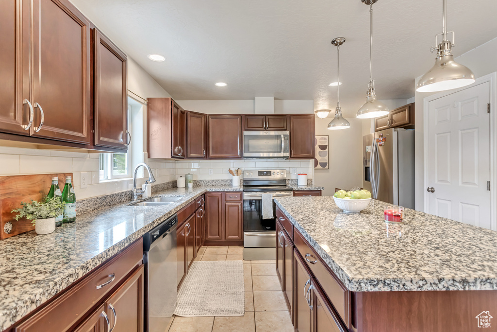 Kitchen with a center island, light tile flooring, backsplash, appliances with stainless steel finishes, and sink