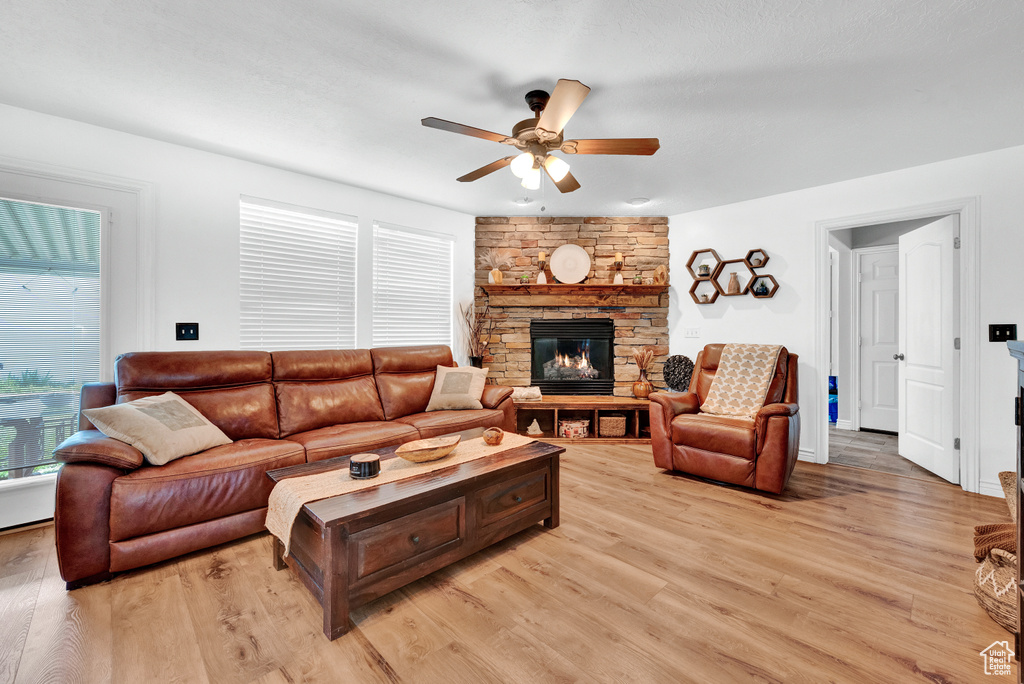 Living room featuring a fireplace, ceiling fan, and light wood-type flooring