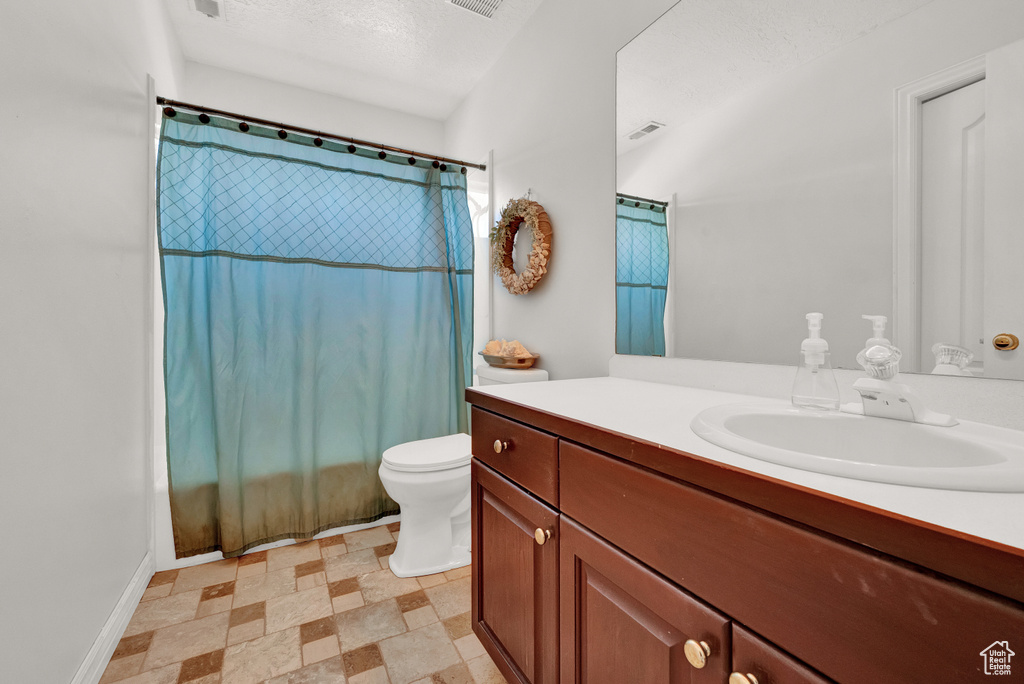 Bathroom with toilet, tile floors, vanity, and a textured ceiling