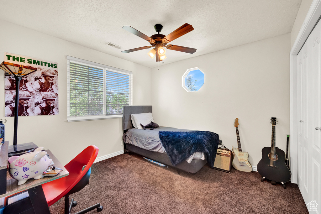 Carpeted bedroom with a closet, a textured ceiling, and ceiling fan