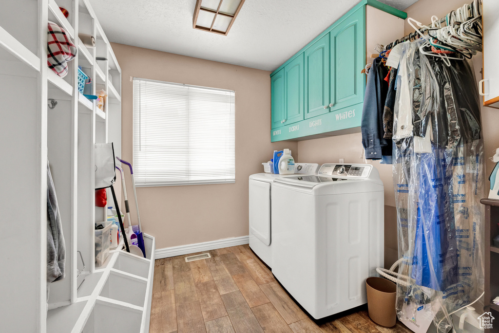 Washroom featuring light hardwood / wood-style flooring, cabinets, and washing machine and dryer