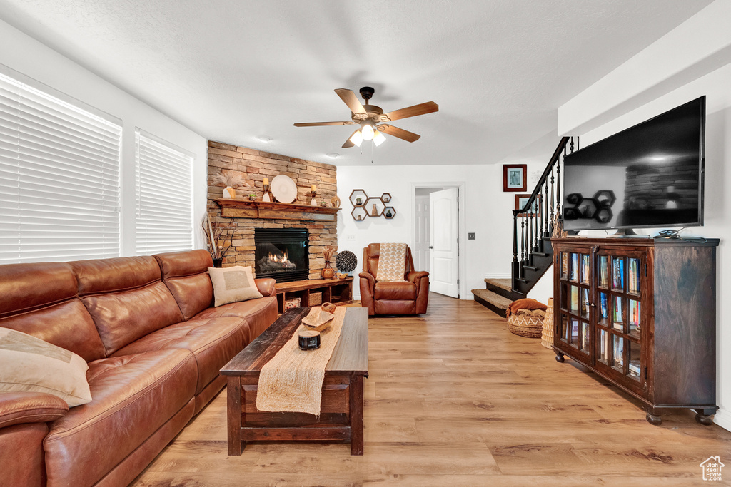 Living room featuring wood-type flooring, ceiling fan, and a fireplace