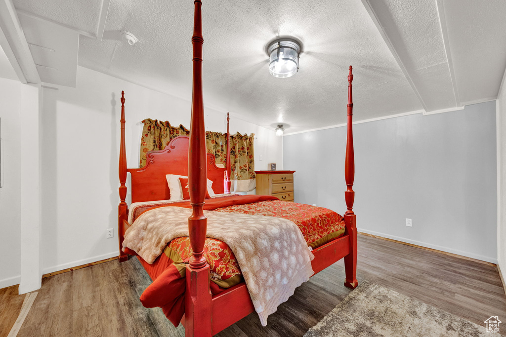 Bedroom with a textured ceiling, crown molding, and hardwood / wood-style flooring