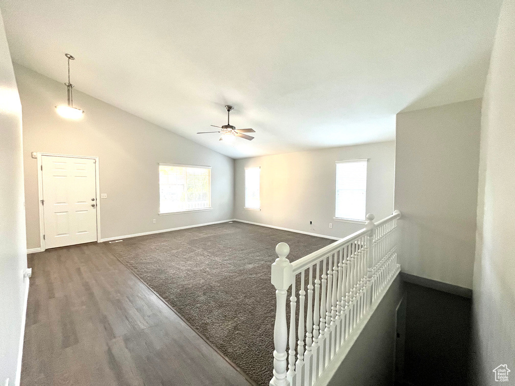 Empty room with lofted ceiling, carpet flooring, and ceiling fan