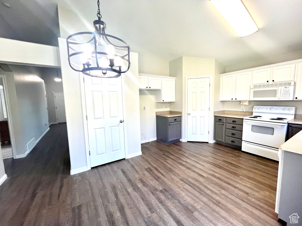 Kitchen with dark wood-type flooring, white cabinets, white appliances, lofted ceiling, and decorative light fixtures