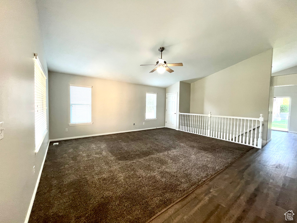 Carpeted spare room with ceiling fan, lofted ceiling, and a wealth of natural light