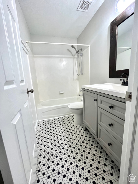 Full bathroom with vanity, bathtub / shower combination, toilet, and a textured ceiling