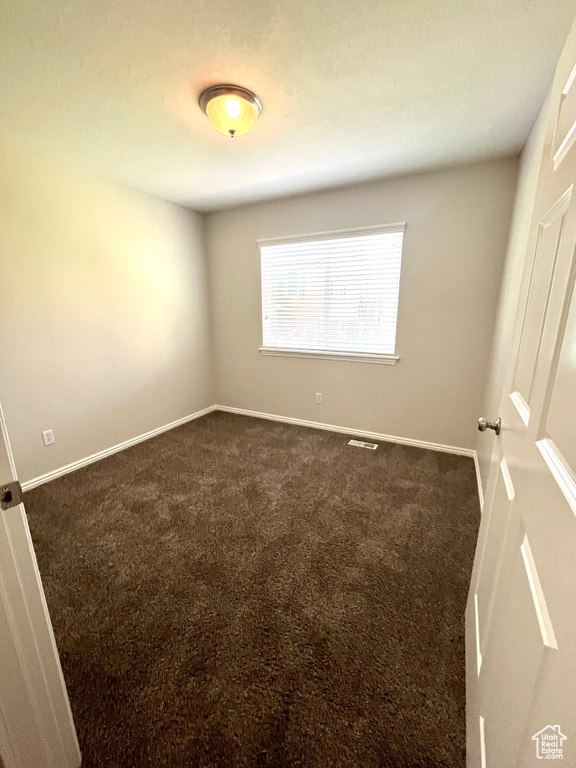 Unfurnished room with dark colored carpet