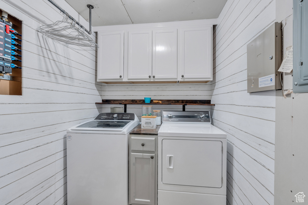 Laundry area featuring cabinets, washer and dryer, and wooden walls